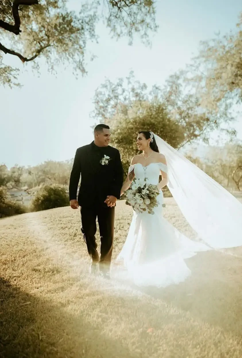 Сouple wearing a white gown and a black suit on the field